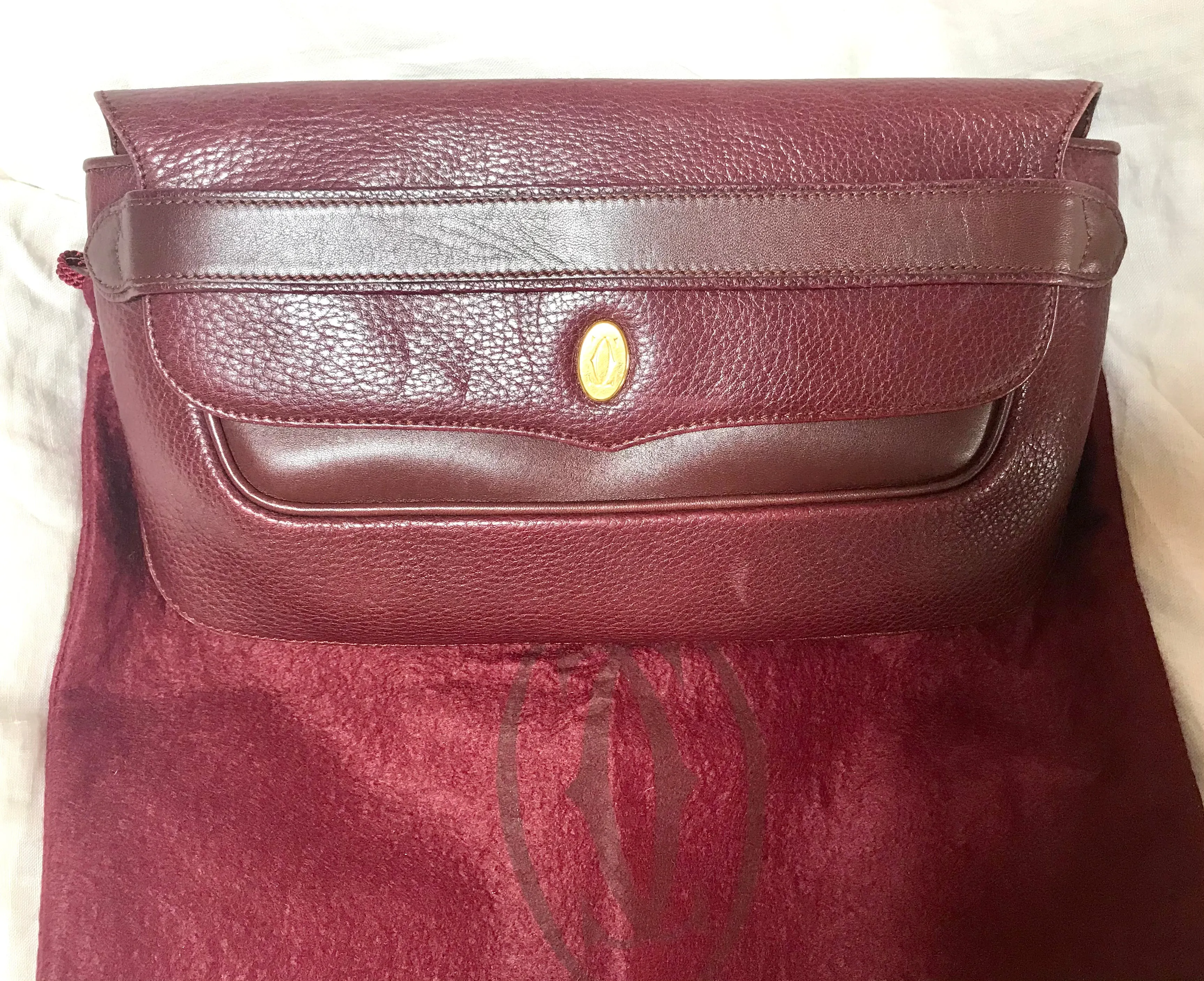 Vintage Cartier wine leather clutch bag with gold tone logo motif. Classic purse from must de Cartier Collection.