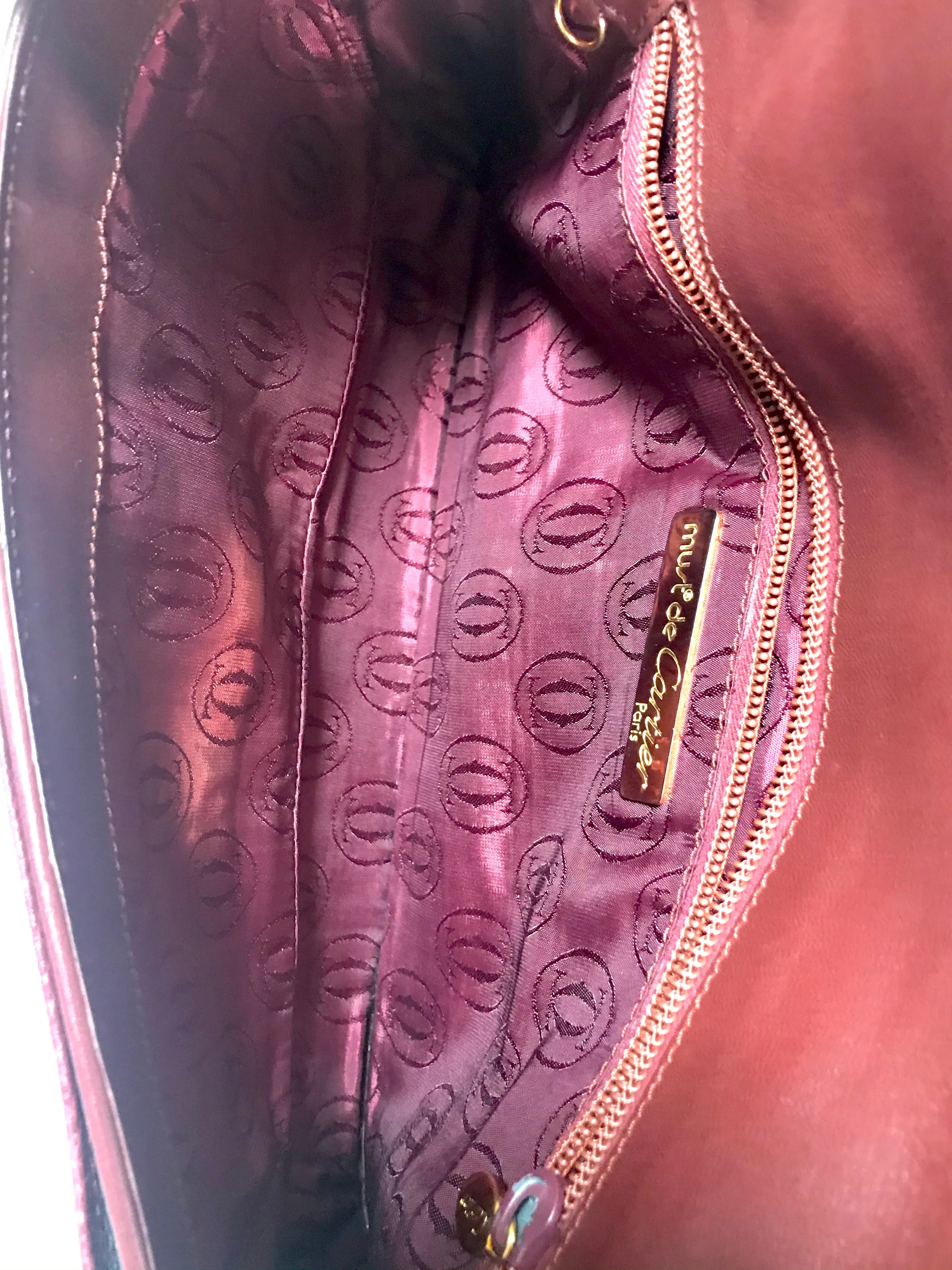 Vintage Cartier wine leather clutch bag with gold tone logo motif. Classic purse from must de Cartier Collection.