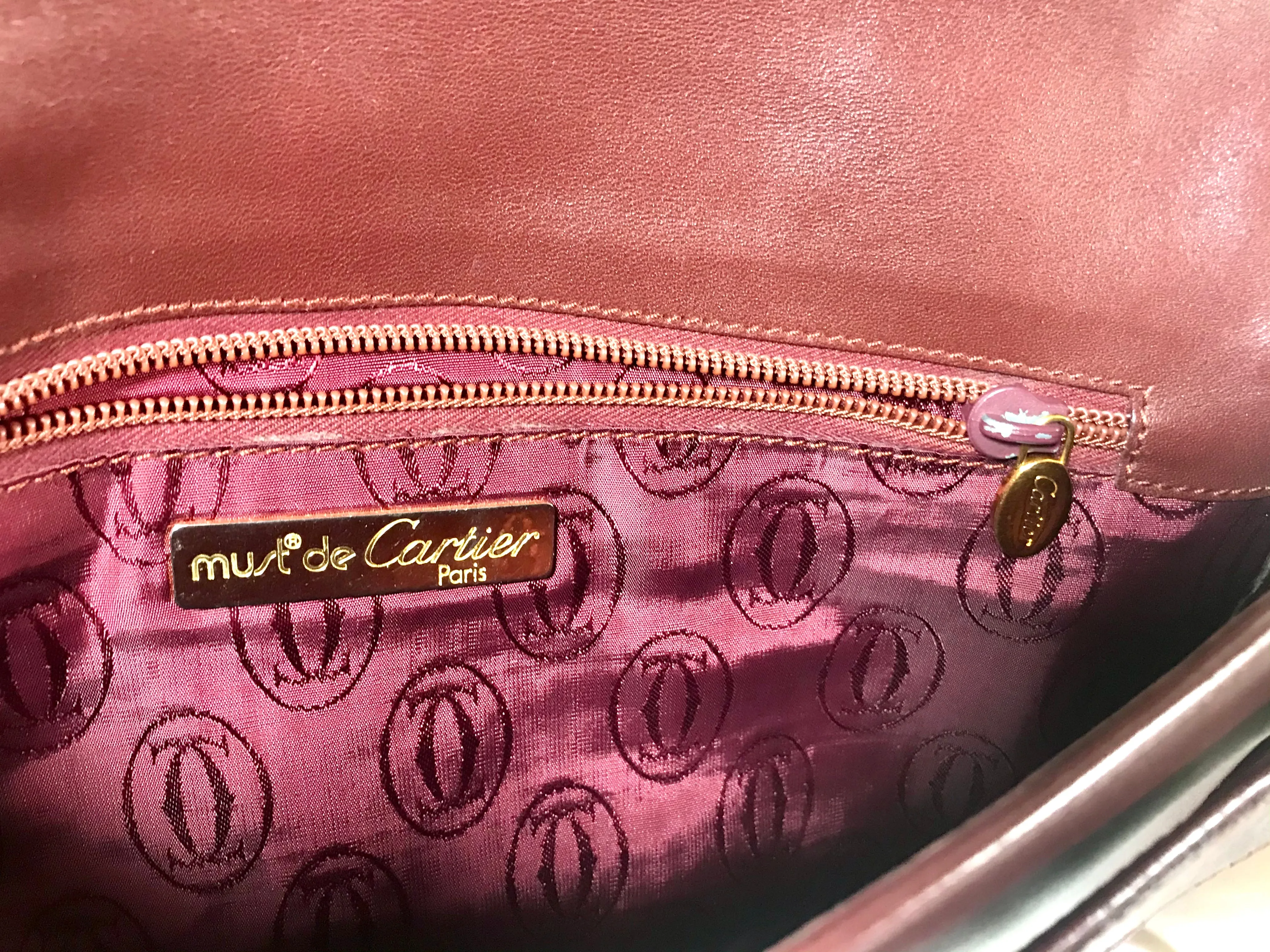 Vintage Cartier wine leather clutch bag with gold tone logo motif. Classic purse from must de Cartier Collection.
