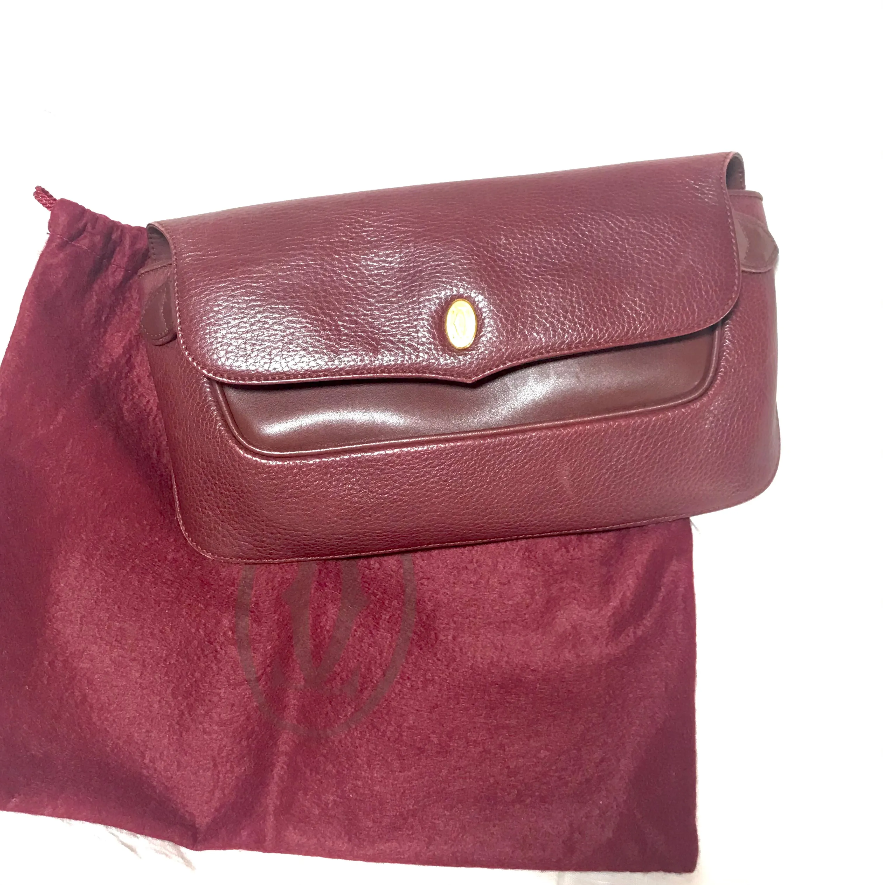 Vintage Cartier wine leather clutch bag with gold tone logo motif. Classic purse from must de Cartier Collection.